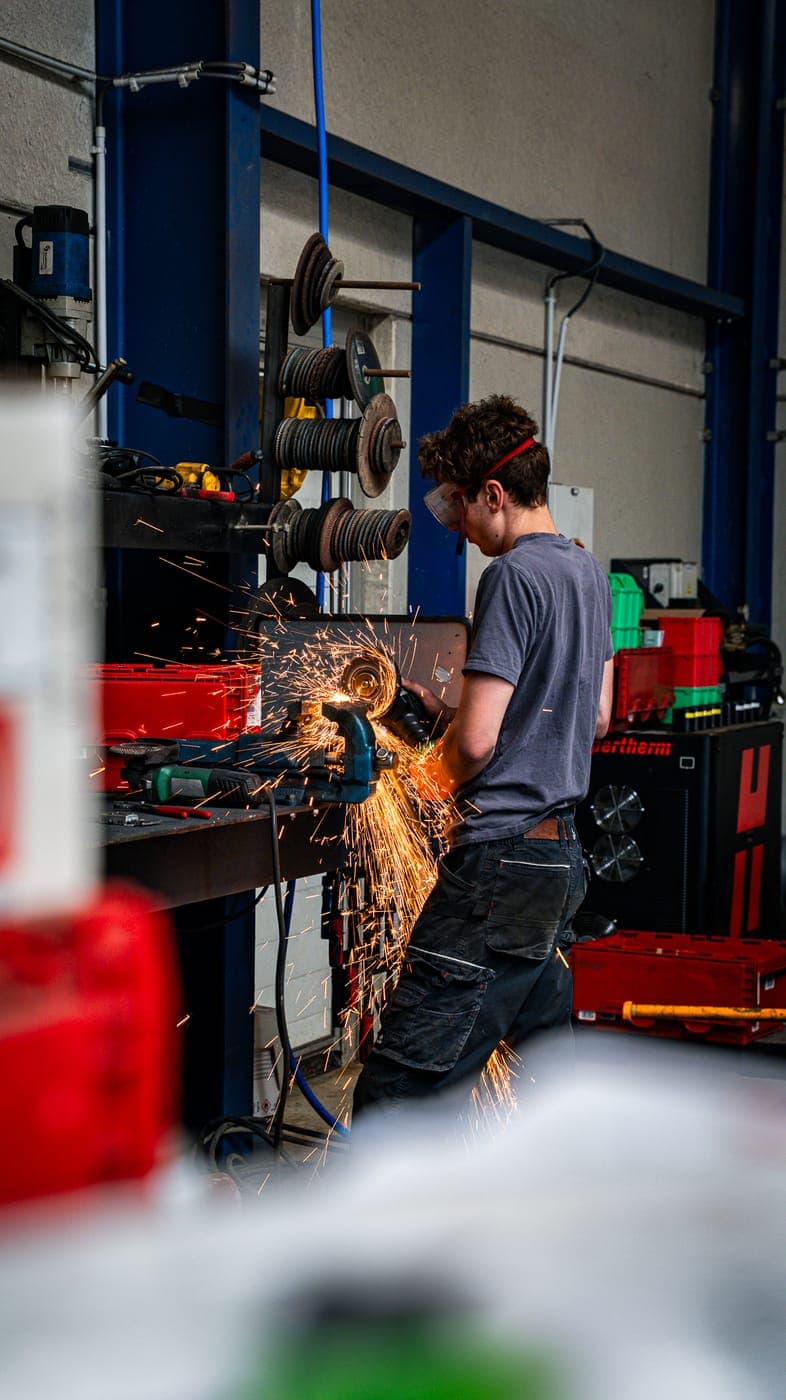 Technicien de l'atelier BGMAT découpant une pièce métallique sur mesure
